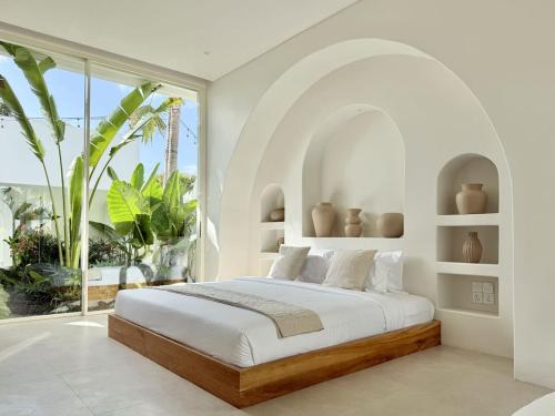 a white bedroom with a large bed and a large window at Dolce Suites in Uluwatu