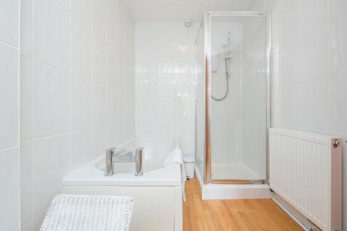 a white bathroom with a shower and a sink at Heddfan Cottage in Haverfordwest