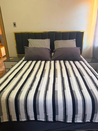 a bed with a black and white striped comforter and pillows at Root&Roam Nature in Malelane