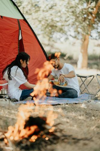 two people sitting around a fire in front of a tent at Above the Clouds Camp in Kintamani