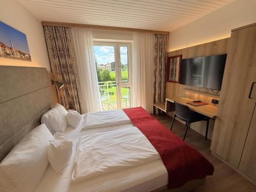 a hotel room with a bed and a desk and a window at Dorf Hotel Grüner Baum in Maria Laach am Jauerling