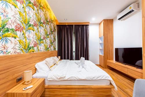 a hotel room with a bed and a tv at King Arthur Pool Villa in Nong Prue