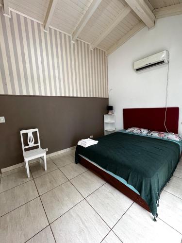a bedroom with a green bed and a white chair at Raíces Vivas Dúplex - Cochera Privada en Oberá in Oberá
