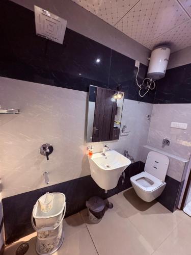 a bathroom with a sink and a toilet and a mirror at The Hotel Sundaram Continental in Prayagraj