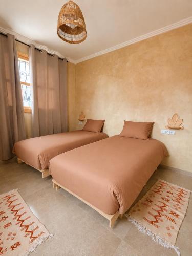 two beds sitting in a room with at Sines Surfmaroc in Tamraght Ouzdar