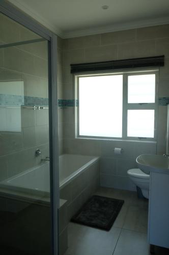 a bathroom with a tub and a toilet and a sink at Igoda Mouth Resort in Winterstrand