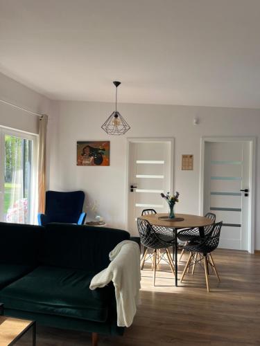 a living room with a green couch and a table at Cisza lasu in Kadłubówka