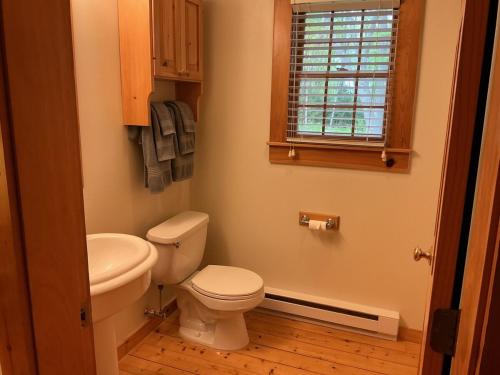 a bathroom with a toilet and a sink and a window at Rivers Edge Cabins - Deer Run in Cushing