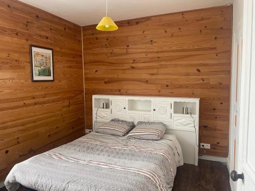 a bedroom with a bed in a wooden wall at Maison de Tisserand 10 pers in Gesté