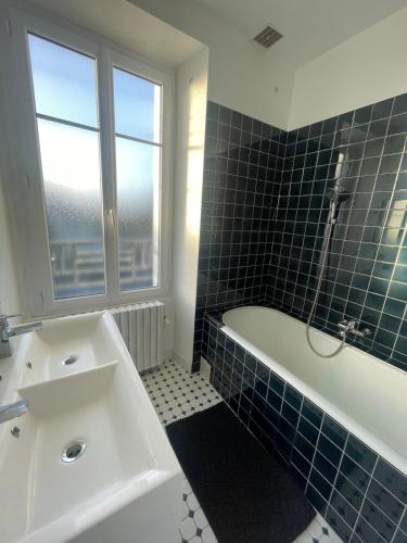 a bathroom with a tub and a sink and a window at Maison de Tisserand 10 pers in Gesté