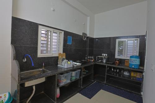 a kitchen with black tiled walls and a sink at Slackpackr Malakpet Hyderabad in Hyderabad