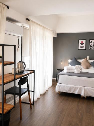 a bedroom with a bed and a table and a desk at El Misti Suites Buenos Aires in Buenos Aires