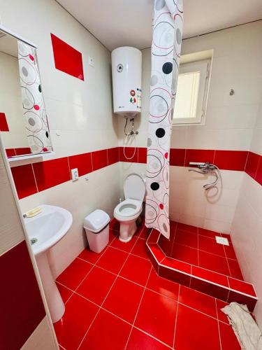a red and white bathroom with a toilet and a sink at 1apartment on First Line-Bosteri in Bosteri