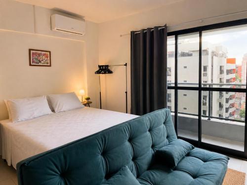 a bedroom with a bed and a couch and a window at TIME Ponta Verde in Maceió
