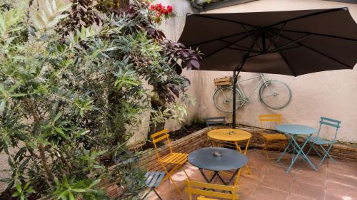 a table and chairs with an umbrella and a bike at Hotel Arc Paris Porte d'Orléans in Montrouge