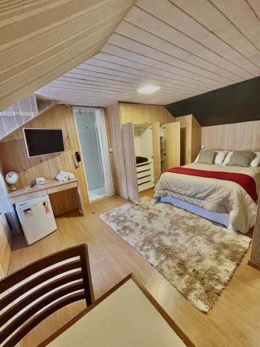 a large bedroom with a bed and a rug at Suites CAMINHO DA FÉ in Campos do Jordão