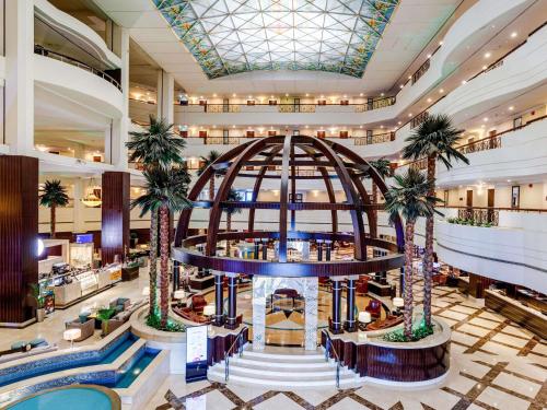 a lobby of a hotel with palm trees at Mövenpick Grand Al Bustan in Dubai