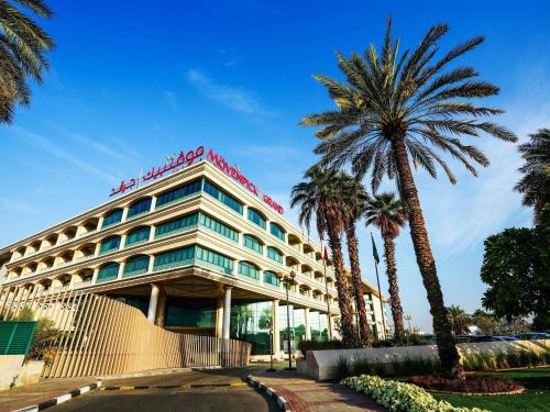 a hotel with a palm tree in front of it at Mövenpick Grand Al Bustan in Dubai