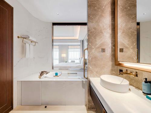 a white bathroom with a sink and a mirror at Sofitel Xiong An in Baoding