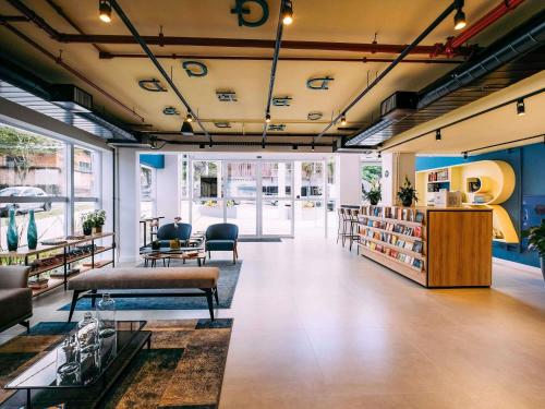 a room with a library with couches and chairs and tables at ibis Styles Poços de Caldas in Poços de Caldas