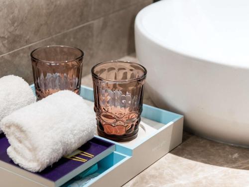 a bathroom with two glasses and towels on a shelf at Mercure Chengdu Wuhou Temple in Chengdu
