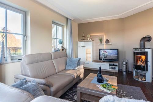 a living room with a couch and a tv at Ferienhaus Strandmuschel mit Sauna in Loddin