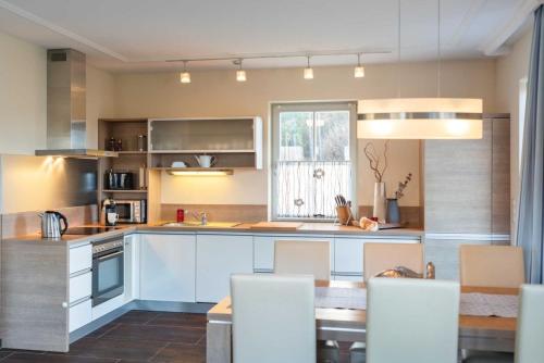 a kitchen with white cabinets and a table and chairs at Ferienhaus Strandmuschel mit Sauna in Loddin