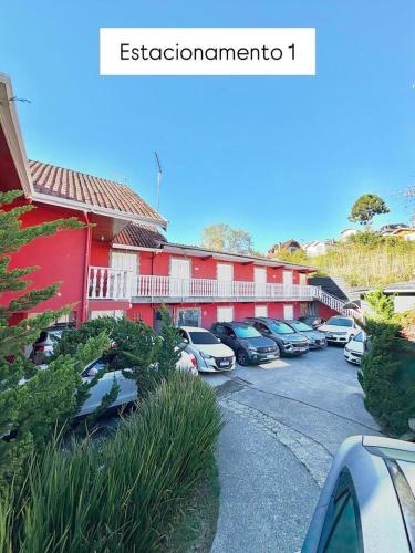 a parking lot with cars parked in front of a building at Suites CAMINHO DA FÉ in Campos do Jordão