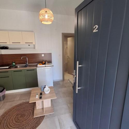 a kitchen with a blue door and a table at Sky Rooms in Nea Kallikrateia