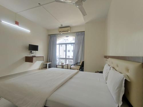 a large white bed in a room with a window at Hotel Rajtara in Satara