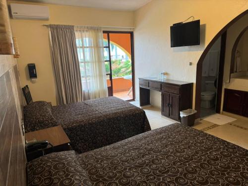 a hotel room with two beds and a desk and a television at Hotel & Motel Hacienda Jiutepec in Jiutepec