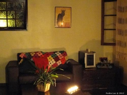a living room with a couch and a cat picture on the wall at Pousada Romântica Serra da Mata in Penedo