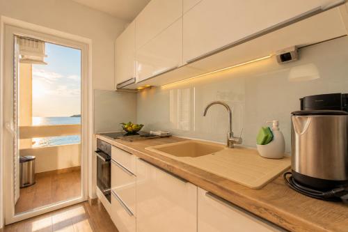 a kitchen with a sink and a counter with a window at Villa Bilic in Rogoznica