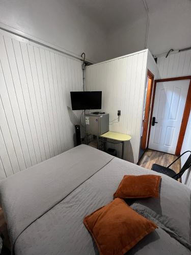 a bedroom with a bed and a desk and a television at VOY Hostales - Poniente in Viña del Mar