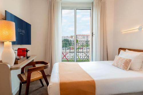 a hotel room with a bed and a desk and a window at Crisol Lumière in Cannes