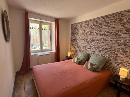 a bedroom with a brick wall and a bed at La maison du père Bellessort in Régnié
