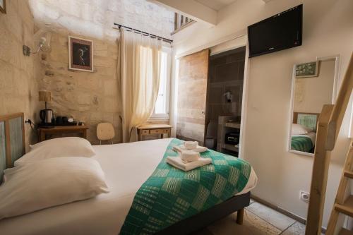 a bedroom with a bed with two towels on it at Hôtel La Muette in Arles
