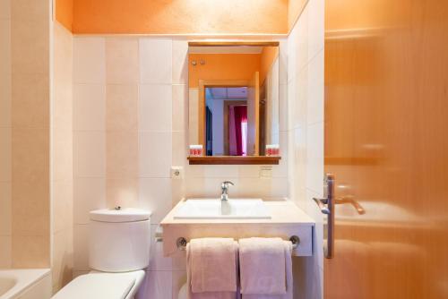 a bathroom with a toilet and a sink and a mirror at Leo Punta Umbría in Punta Umbría