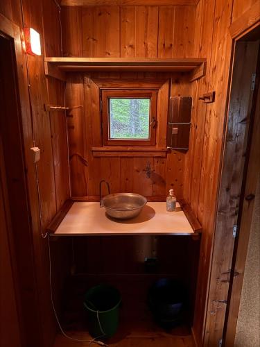 a wooden bathroom with a sink and a window at Simple and cozy forest cabin in Eidsstryken