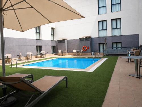 a pool with chairs and tables and an umbrella at Hotel Pedro I de Aragón 4 Sup in Huesca