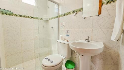a white bathroom with a toilet and a sink at Pousada Porto Amazônia in Porto De Galinhas