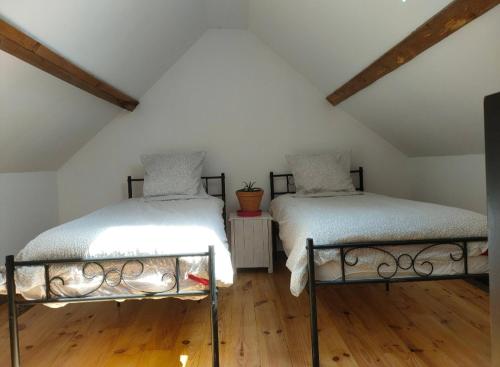 two beds in a attic room with wooden floors at Chrisme in Saint-Hilaire-Fontaine