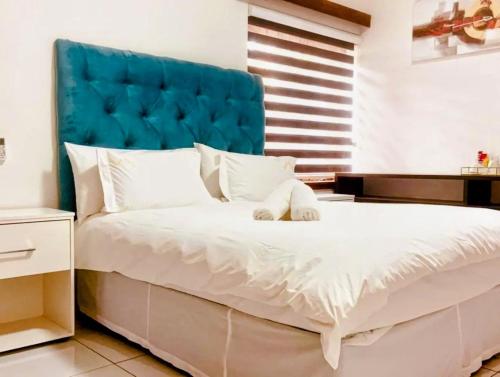 a bedroom with a large bed with a blue headboard at Victoria City Lodge in Pretoria