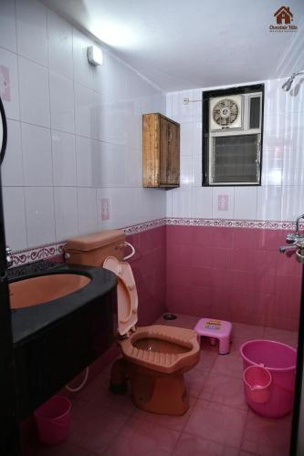 a pink bathroom with a toilet and a sink at CHOCOLATE VILLA Mahabaleshwar in Mahabaleshwar