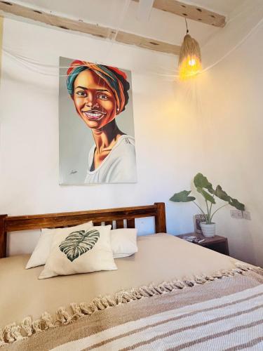 a bedroom with a painting of a woman on the wall at Jambiani Kite Lodge in Jambiani