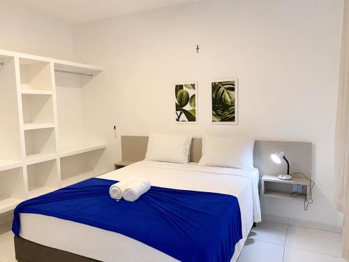 a bedroom with a large bed with a blue blanket at Hosts BR - Apartamentos funcionais in Fortaleza