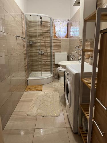 a bathroom with a shower and a washing machine at Apartmani Žak in Pridraga