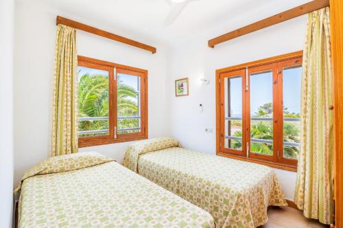 two beds in a room with two windows at Can Jordi in Cala Llombards