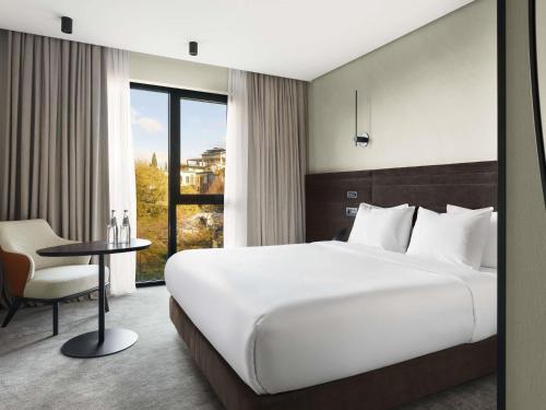 a hotel room with a large bed and a table at Novotel Tbilisi Center in Tbilisi City