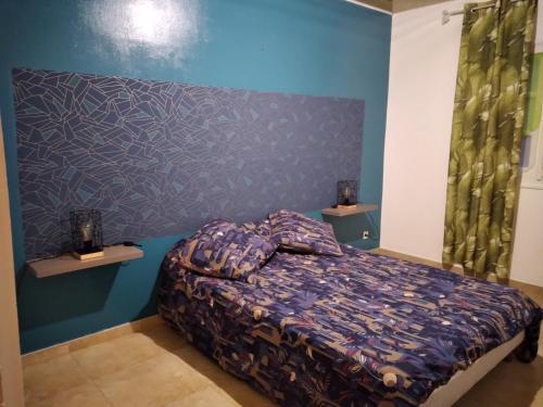 a bedroom with a bed and a blue wall at Le camphrier in Salazie